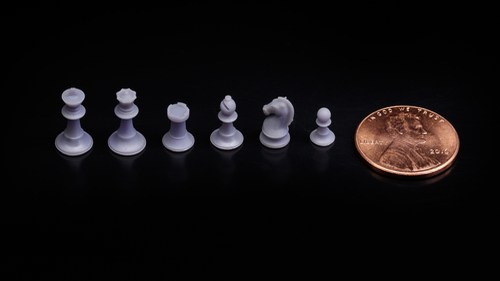Miniatures of chess pieces next to a penny for scale